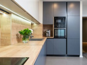Creative design of kitchen with flowers in vase on table against coffeemaker and oven built in cupboard at home